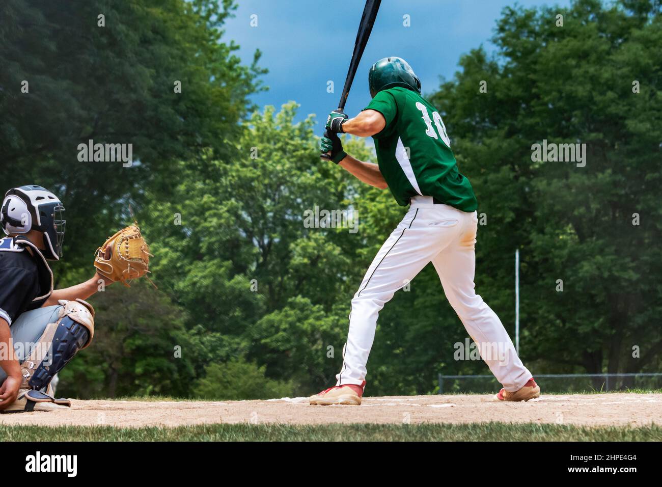A batter and catcher await the pitch.  Adult male baseball players. Stock Photo