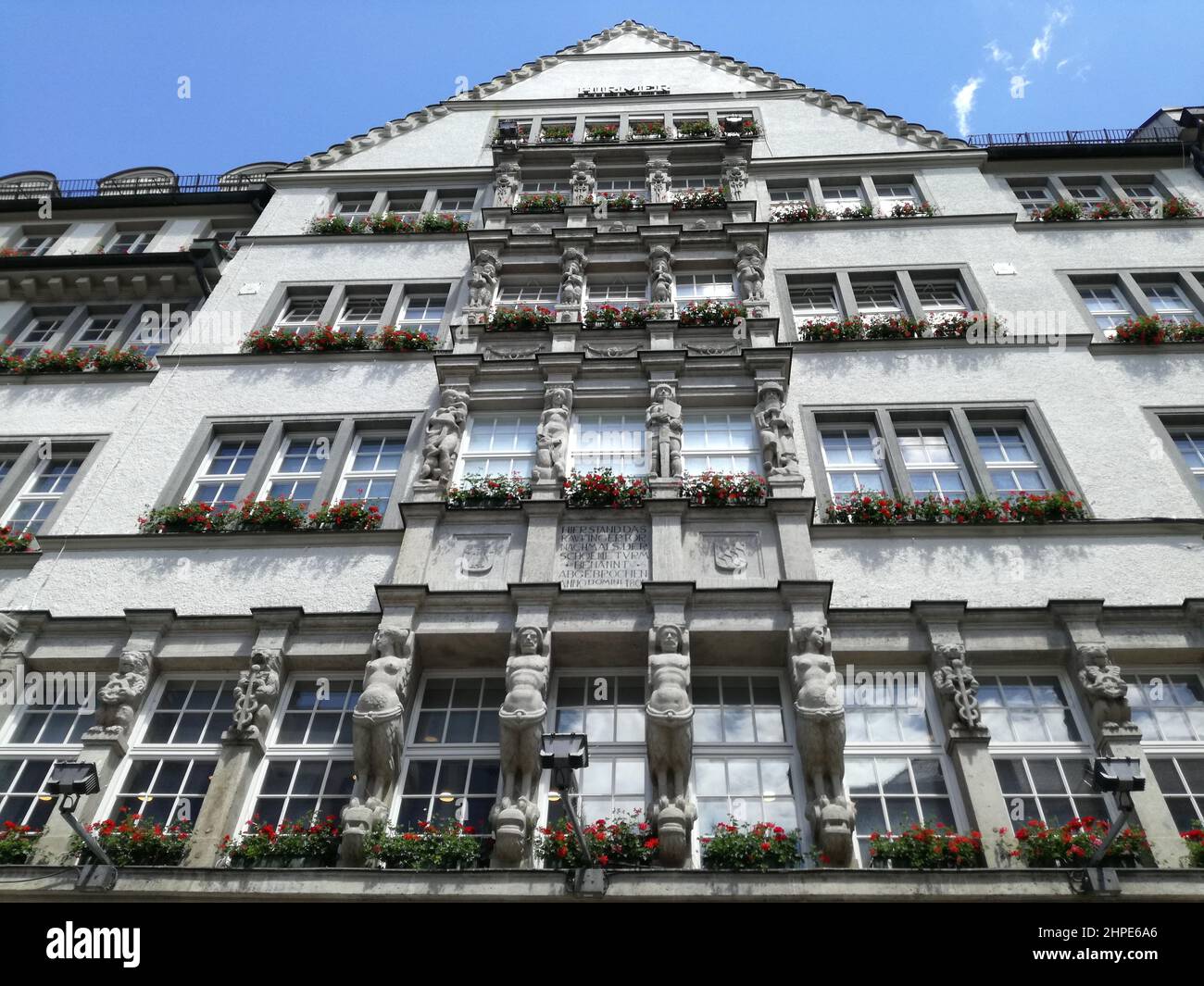 Low angle shot of a white building facade with flowers on balconies ...