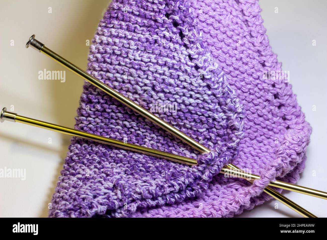 Full frame macro abstract texture background of hand-knitted yarn fabric in a basic garter stitch, in varying shades of purple and white Stock Photo