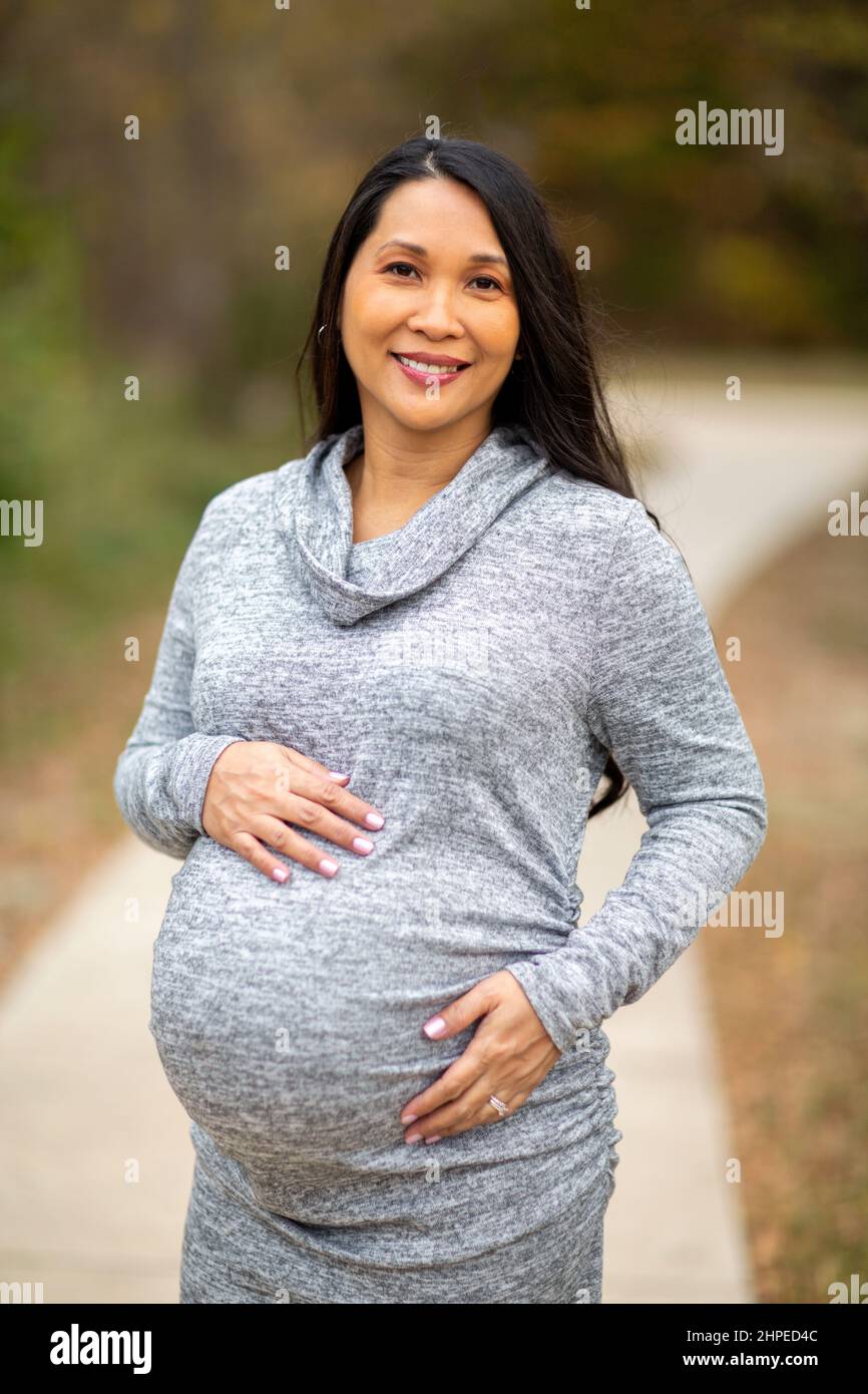 Happy Asian pregnant woman holding her stomach Stock Photo