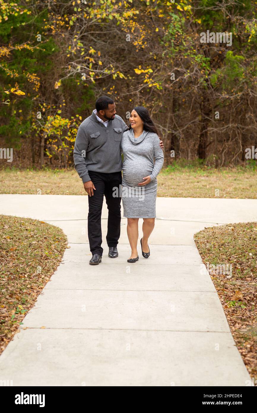 Pregnant Couple Walking And Holding Hands at the park Stock Photo