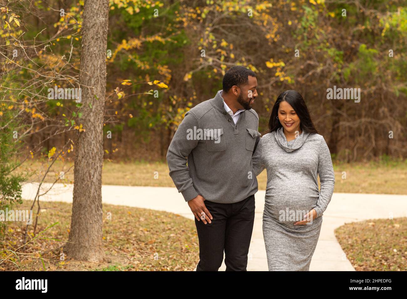 Pregnant Couple Walking And Holding Hands at the park Stock Photo