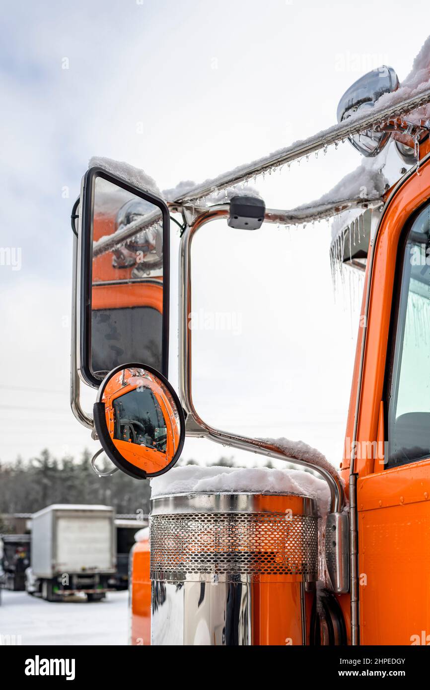 Professional long haul classic orange big rig semi truck tractor with extended cab standing without semi trailer for truck driver rest on the winter t Stock Photo