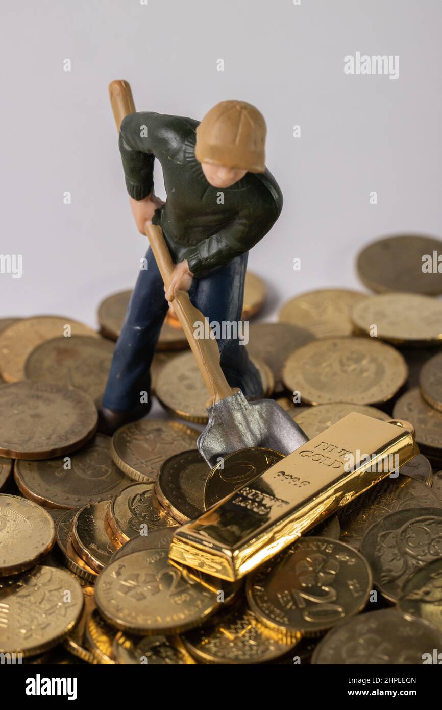 A miniature figurine man posing as a bank manager standing on some coins  with people sitting down Stock Photo - Alamy