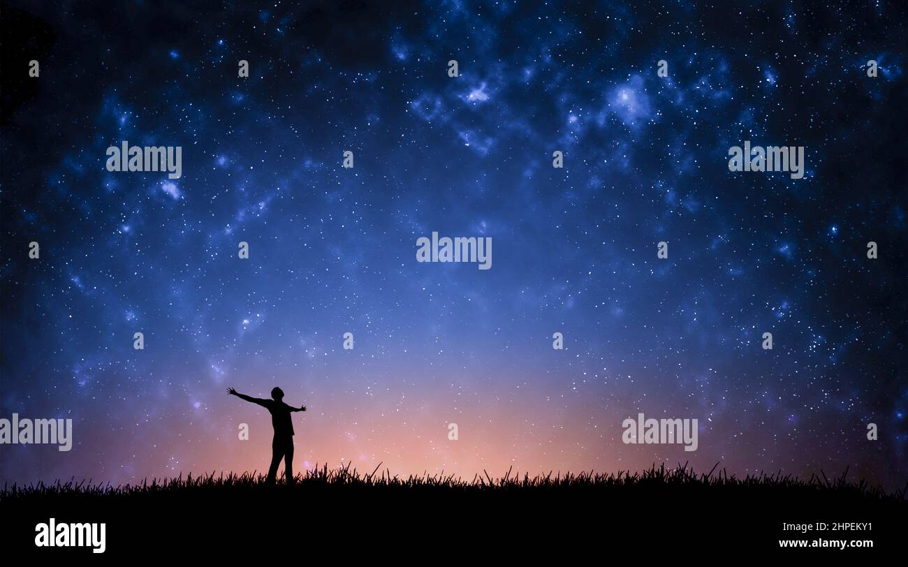 Night landscape with Milky Way. Silhouette of a standing young man with ...