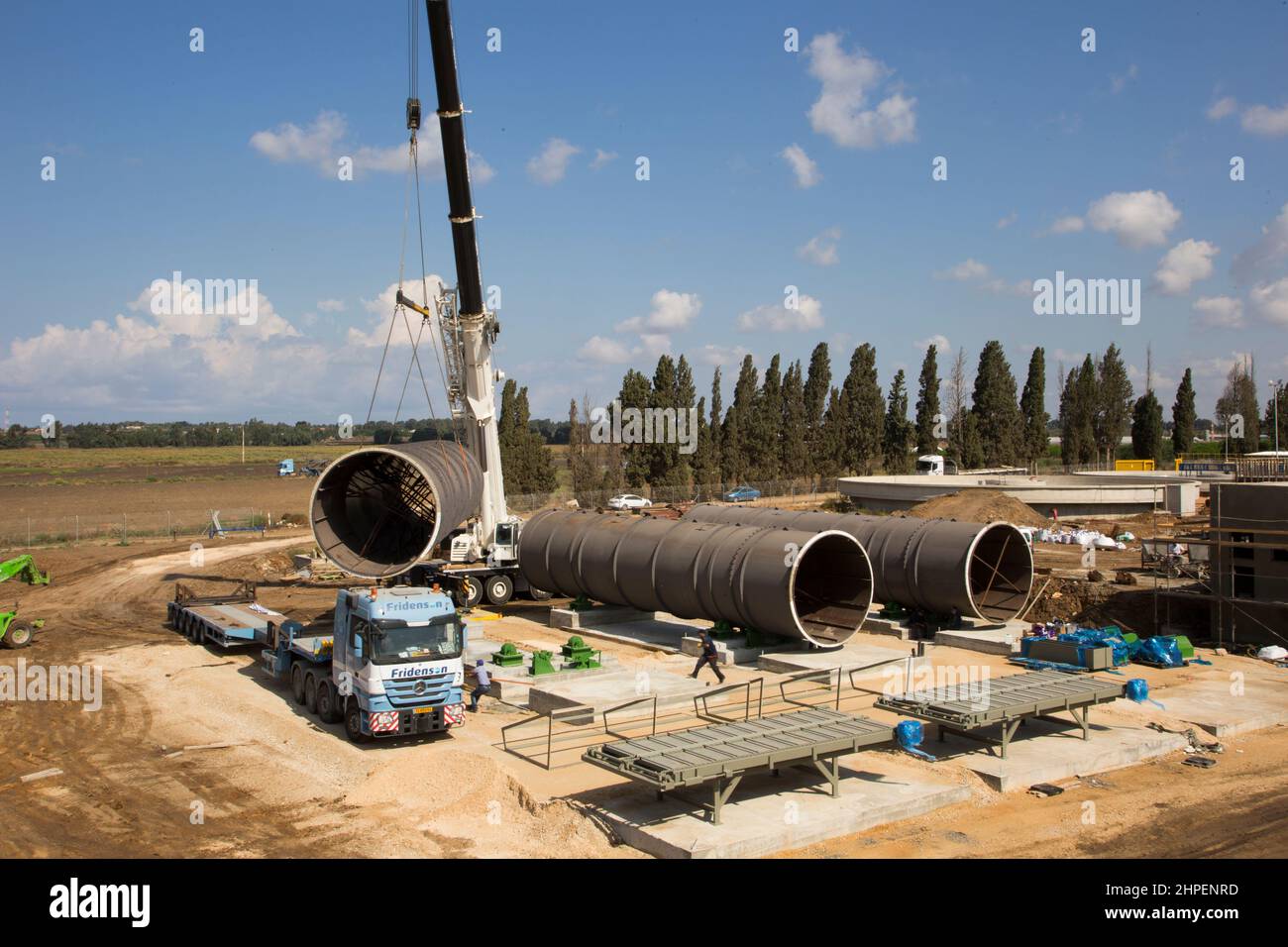 Cranes and pipes for transporting water Tractors and trucks in construction work in a new settlements in Israel Stock Photo