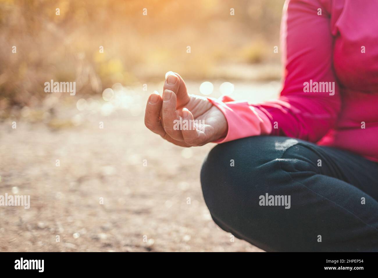 Close up of woman hands sitting in yoga lotus pose outdoor at sunrise, meditation for balance. Horizontal banner with copy space for text. Stock Photo