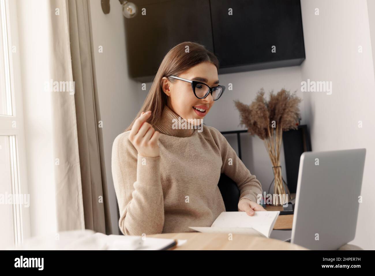 Beautiful young woman working on laptop computer while sitting at the living room, drinking coffee. Home office during Coronavirus or Covid-19 quarant Stock Photo