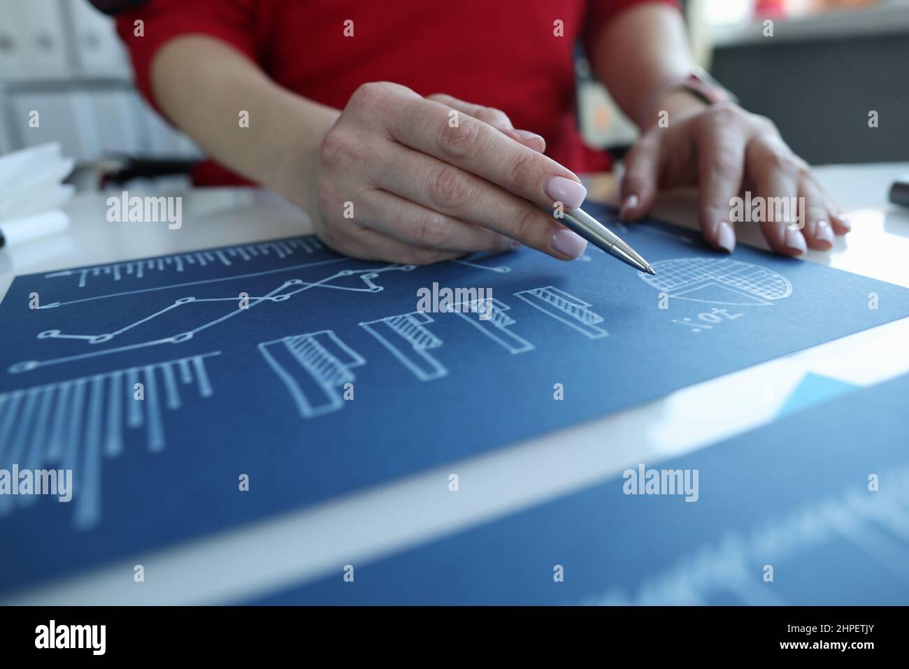 Manager studying documents with statistical graphs on blue paper ...