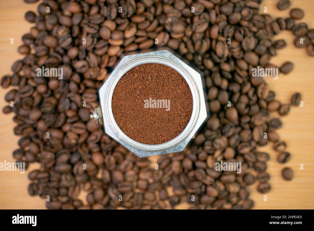 Stove top coffee machine moka percolator filled with ground coffee, surrounded by coffee beans Stock Photo