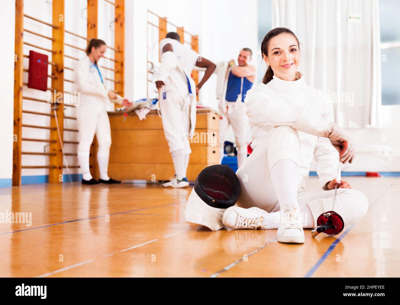 Woman in uniform sitting on floor at fencing training Stock Photo