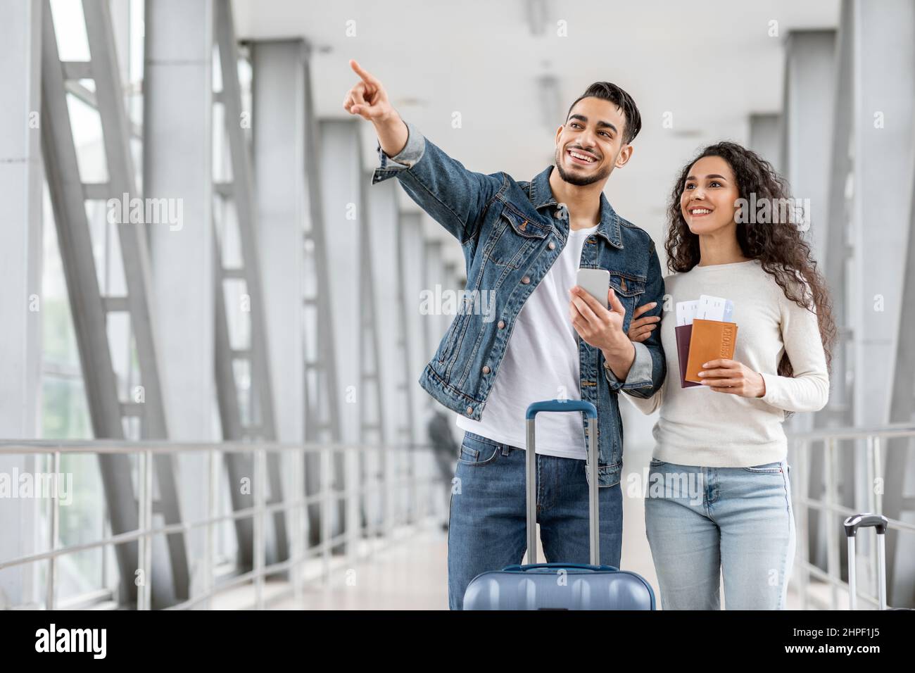 Happy Arab Couple With Smartphone Standing At Airport And Pointing Away ...