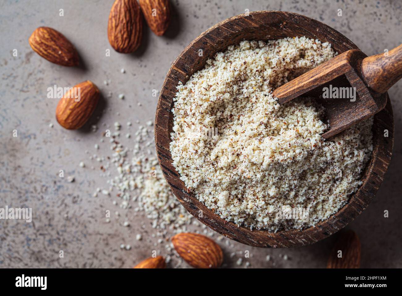 Almond flour in a wooden bowl, top view. Alternative nut flour. Keto