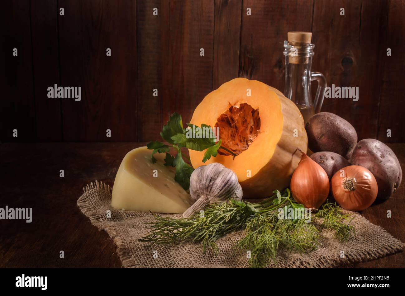 pumpkin and ingredients for pumpkin casserole with potatoes and cheese on a dark background Stock Photo