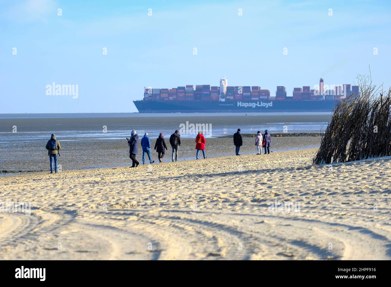 12.02.2022, Cuxhaven, Niedersachsen, Deutschland  - Spaziergaenger am Strand von Cuxhaven bei Ebbe an einem Wintertag im Februar am Rande der Fahrrinn Stock Photo