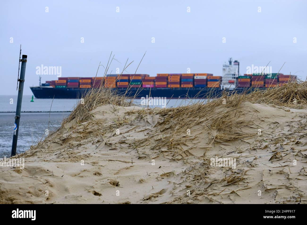 10.02.2022, Cuxhaven, Niedersachsen, Deutschland  - Containerschiff in der Elbmuendung, gesehen vom Strand von Cuxhaven bei Ebbe an einem Wintertag im Stock Photo