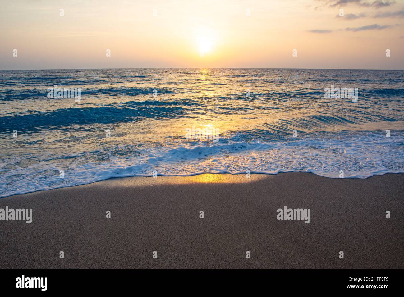 Beautiful sunset on the sea sandy beach. Waves and foam shimmer with ...