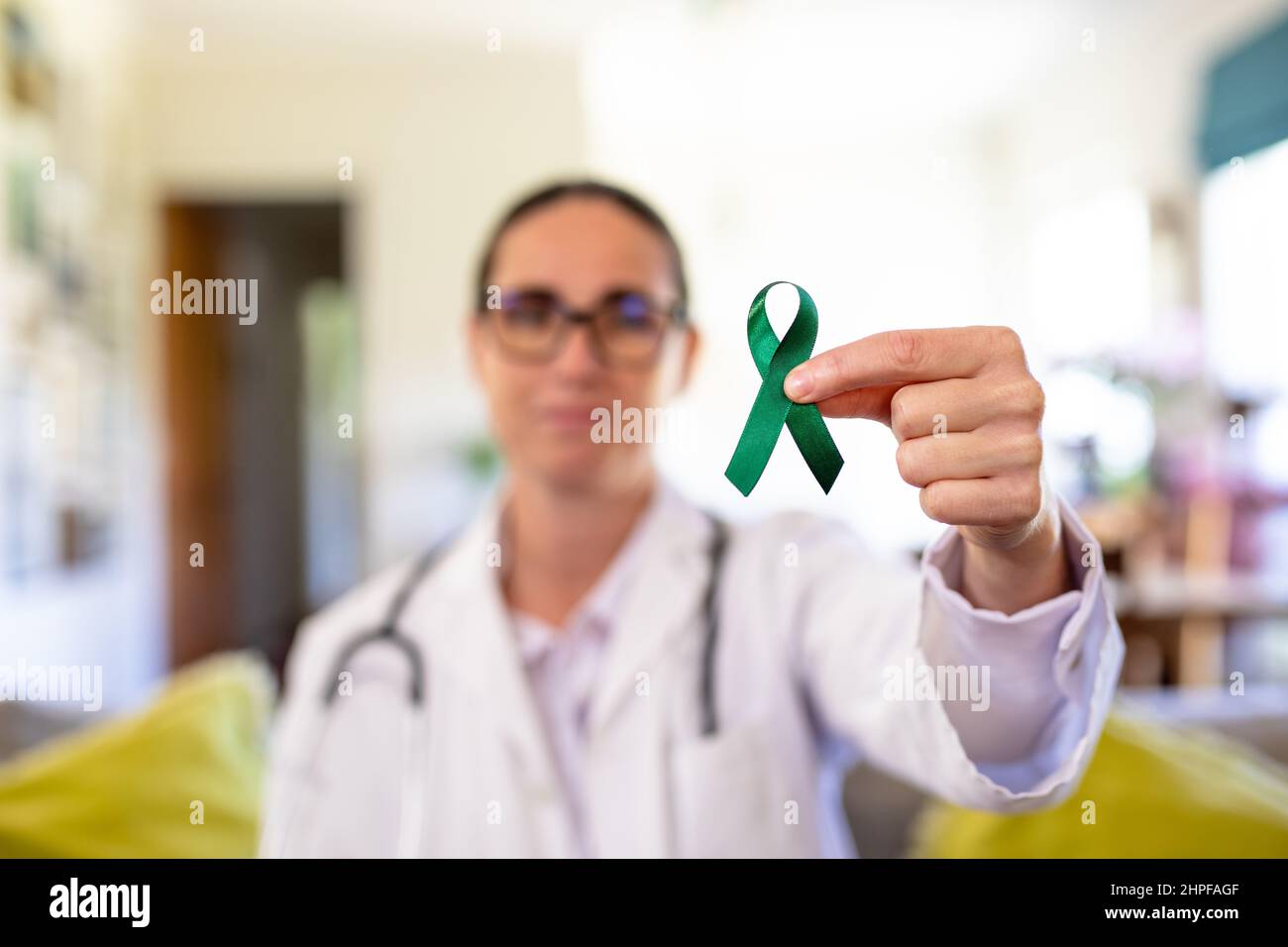 Mature caucasian female doctor showing mental health awareness ribbon, copy space Stock Photo