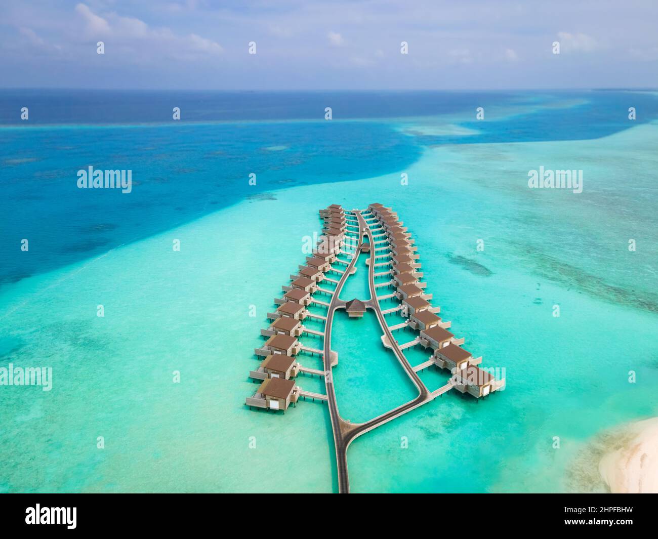 Overwater villas and white sand beach on tropical island for holidays vacation travel and honeymoon. Luxury resort hotel in Maldives or Caribbean with Stock Photo