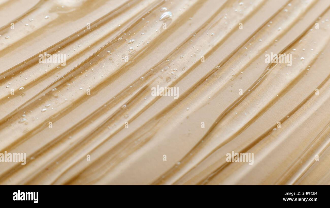 Clear watery gel texture of cosmetic moisturizing product on beige light skin color background. Hyaluronic acid gel or collagen background texture on Stock Photo
