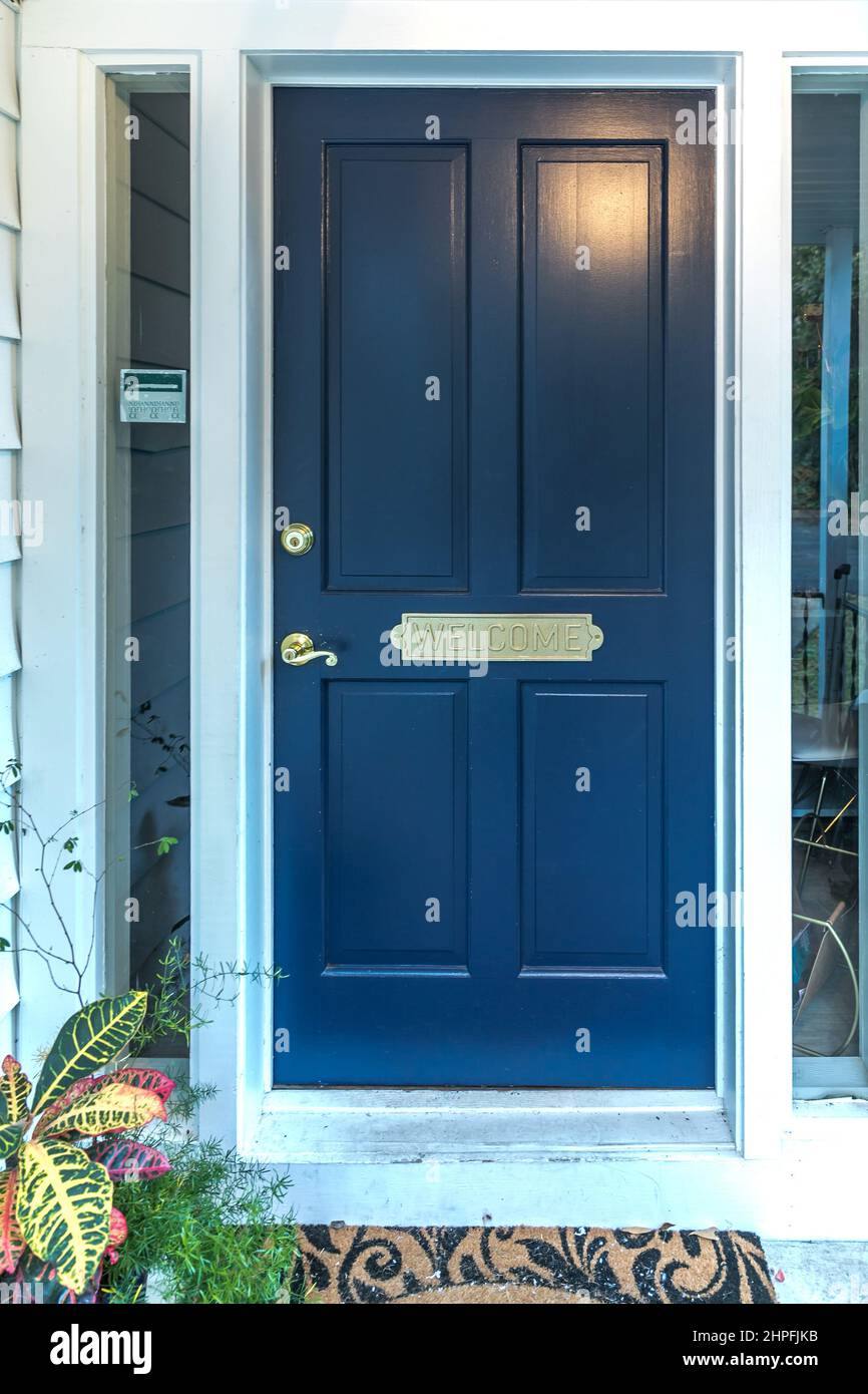 A navy blue front door of a commercial location building with a welcome mat Stock Photo