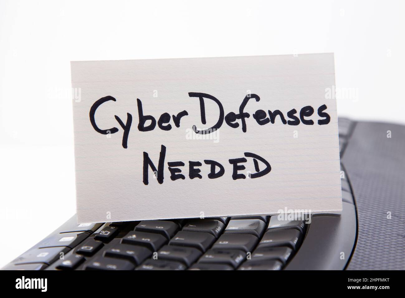 Card lettered Cyber Defenses NEEDED placed on black keyboard reflects protection needs against digital threats Stock Photo