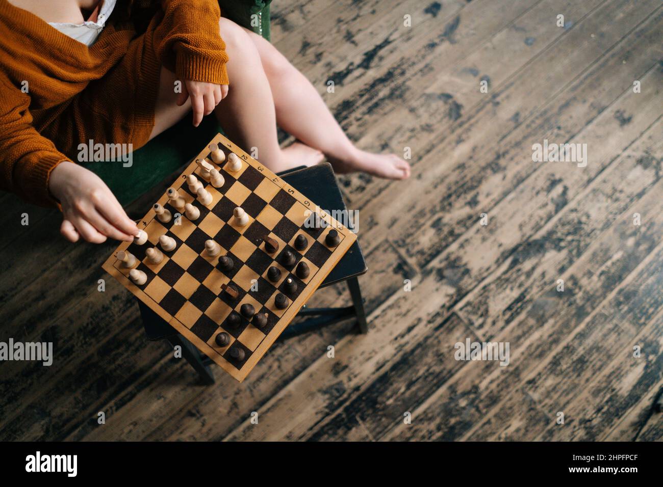 Close-up top view of unrecognizable woman making chess move sitting on ...