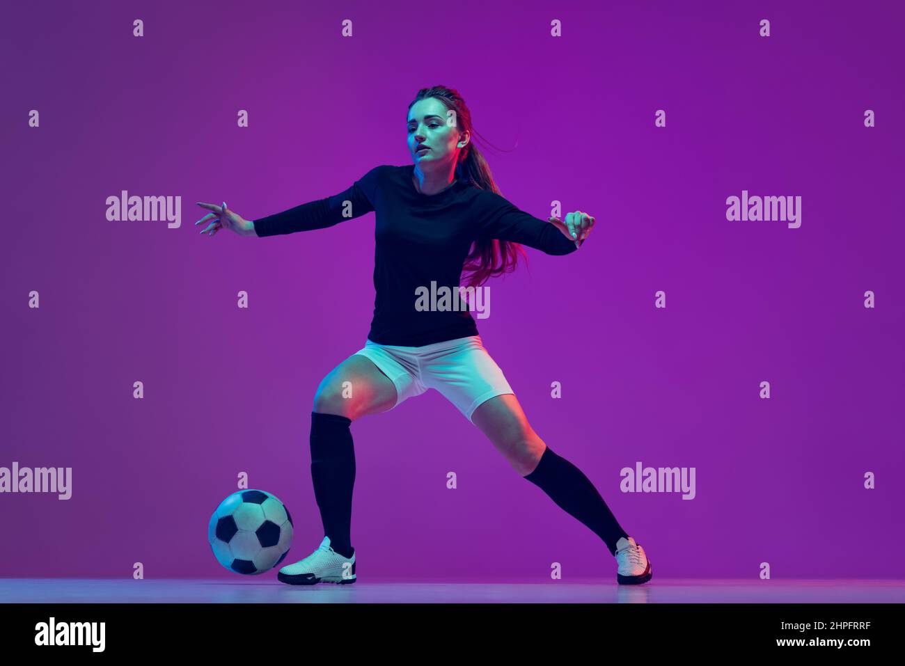 Professional female soccer player dribbling football ball isolated on