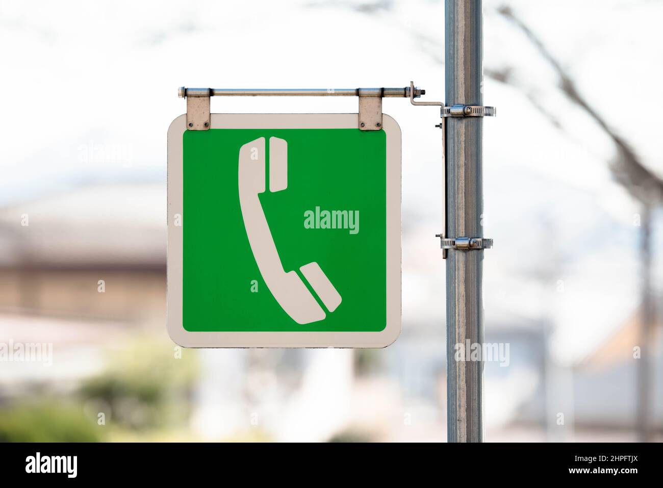 Hanging telephone public pay phone sign on a pole. Color green Stock Photo