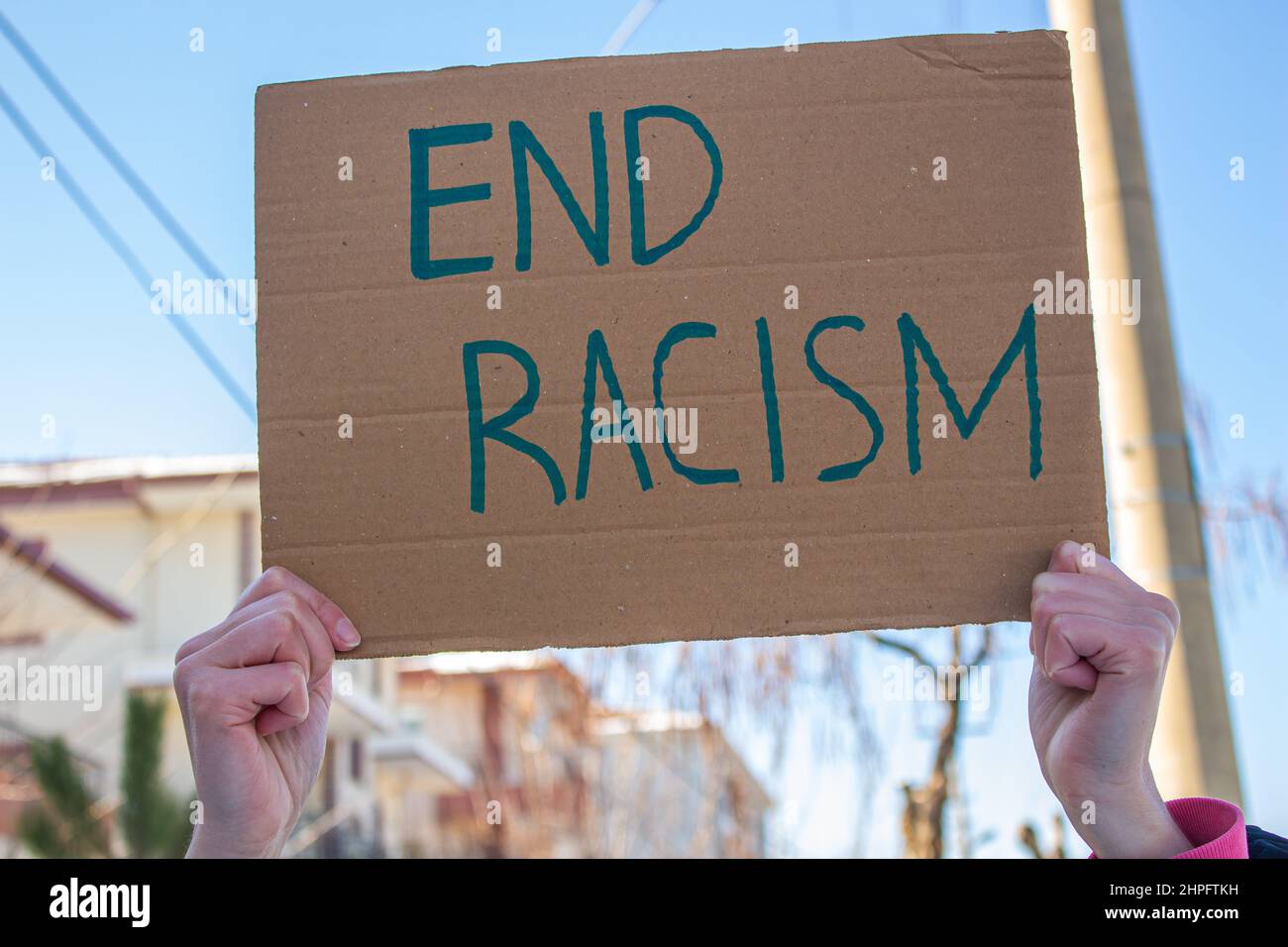 Hand holding cardboard box with end racism text. Woman is protesting racism. Stock Photo