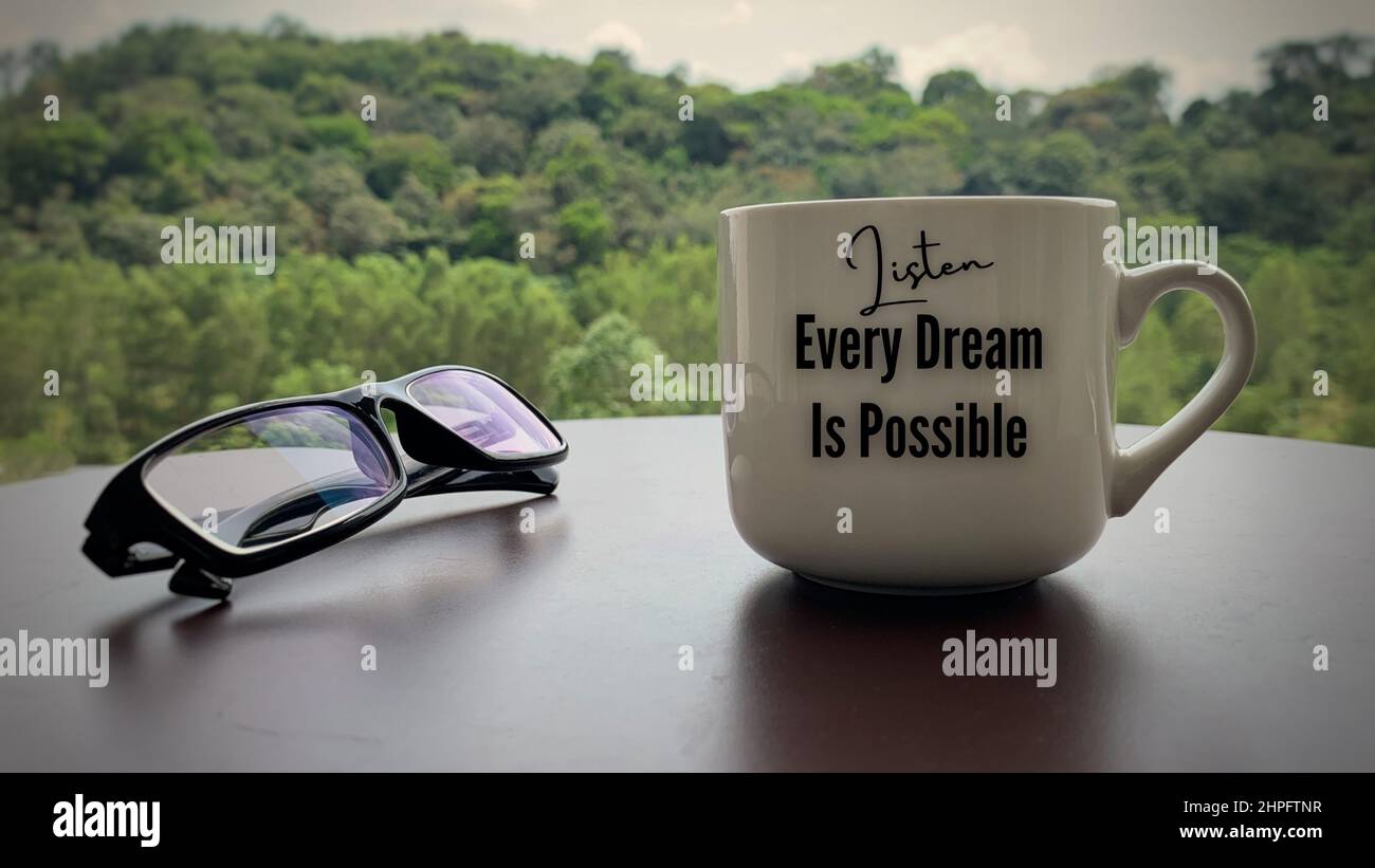 Motivational and inspirational quote on coffee cup - Every Dream Is  Possible. With glasses and blurred nature background Stock Photo - Alamy