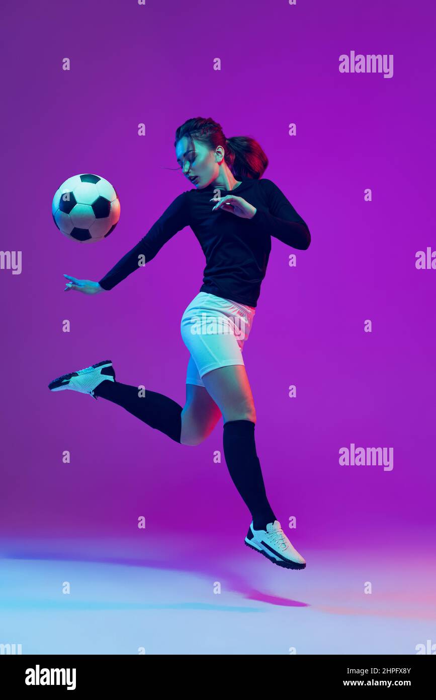 Dynamic portrait of female soccer player practicing with football ball