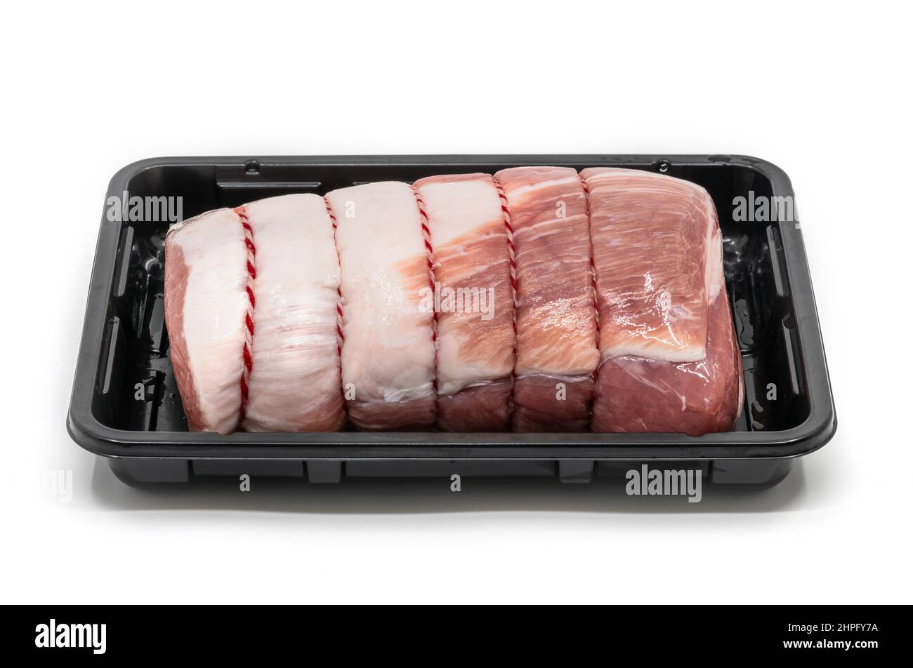 Close up a raw cut of pork loin, tied up and rolled with butcher's string in a black plastic container, 45-degree angle view, the isolated image on wh Stock Photo