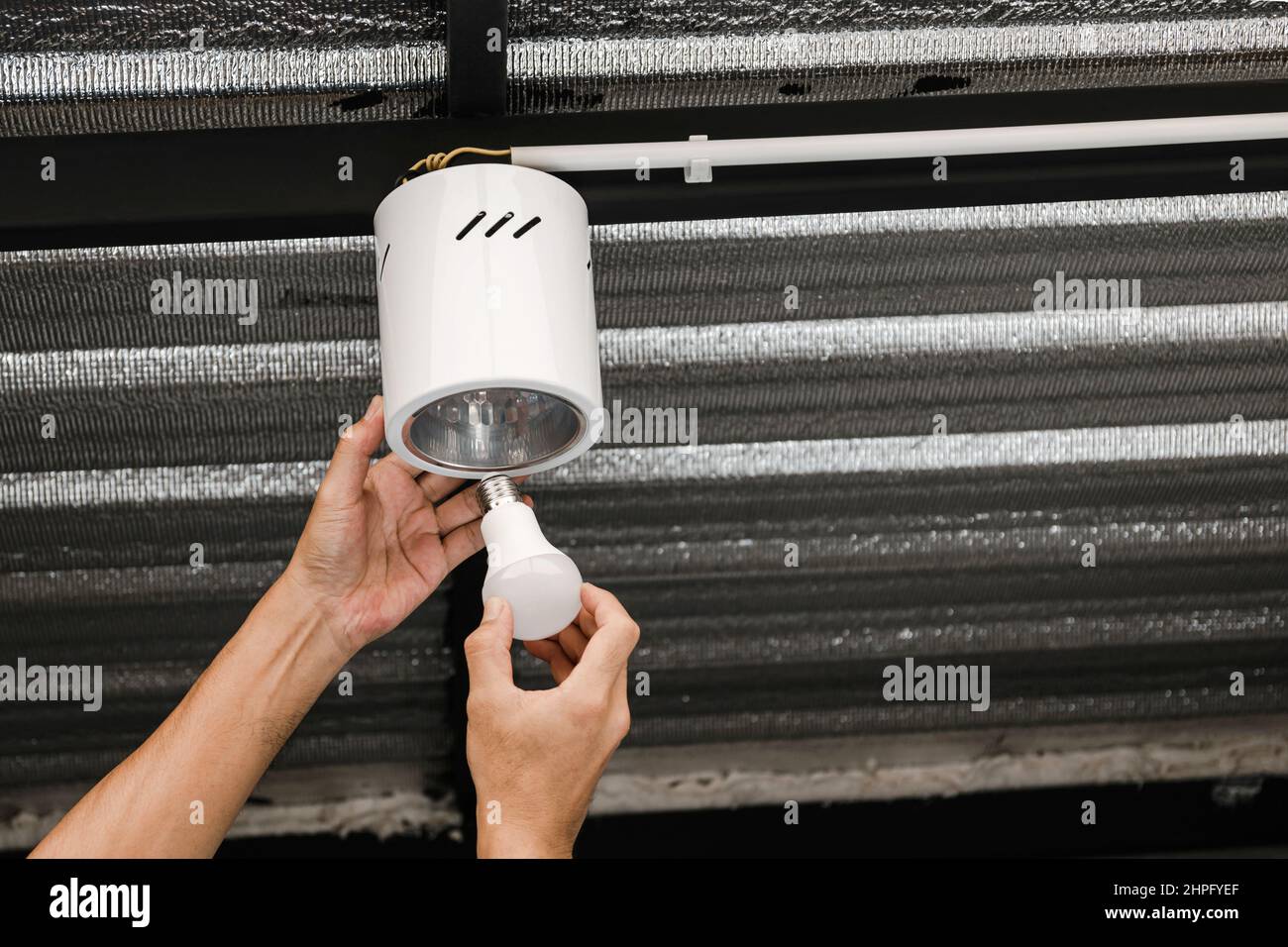 Close up human hand is installing an LED light bulb in a circular ...
