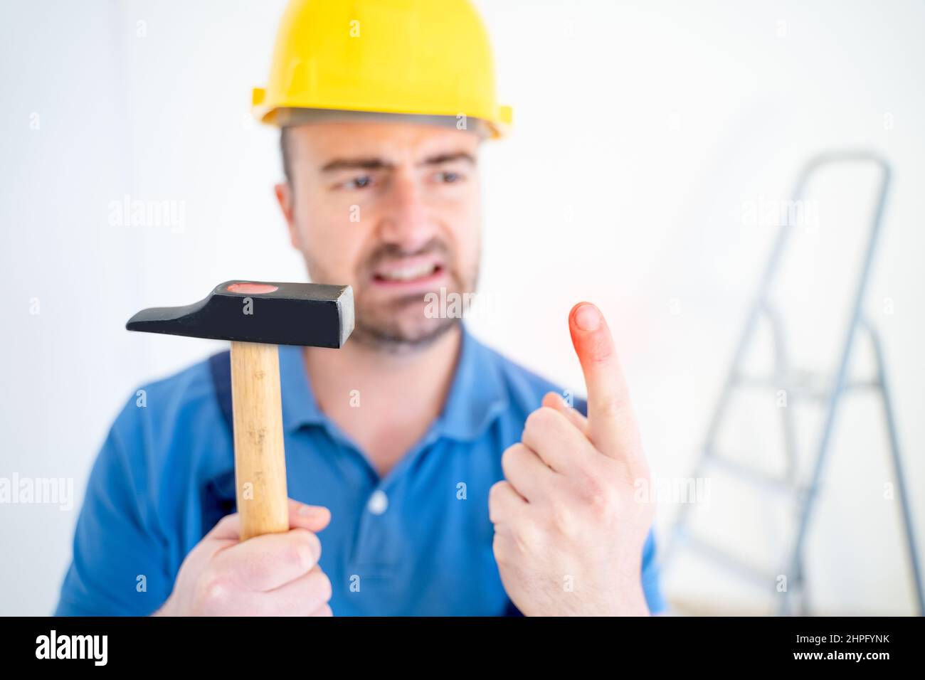 Worker suffering after on the job injury in construction site, focus on the finger Stock Photo
