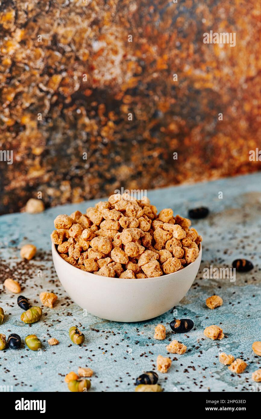 closeup of a bowl with some chunks of textured soy protein on a blue rustic wooden table Stock Photo