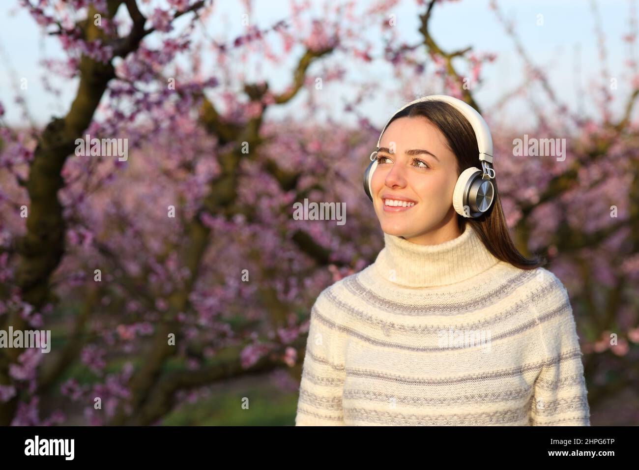 Happy woman in winter wearing headphones listening to music in a field Stock Photo