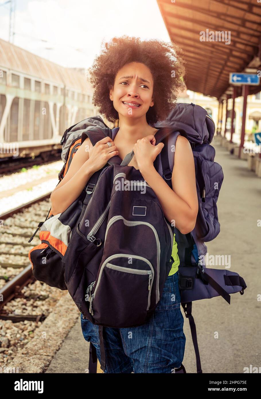 Beautiful tourist traveler standing with huge luggage at the railway station near the tracks Stock Photo