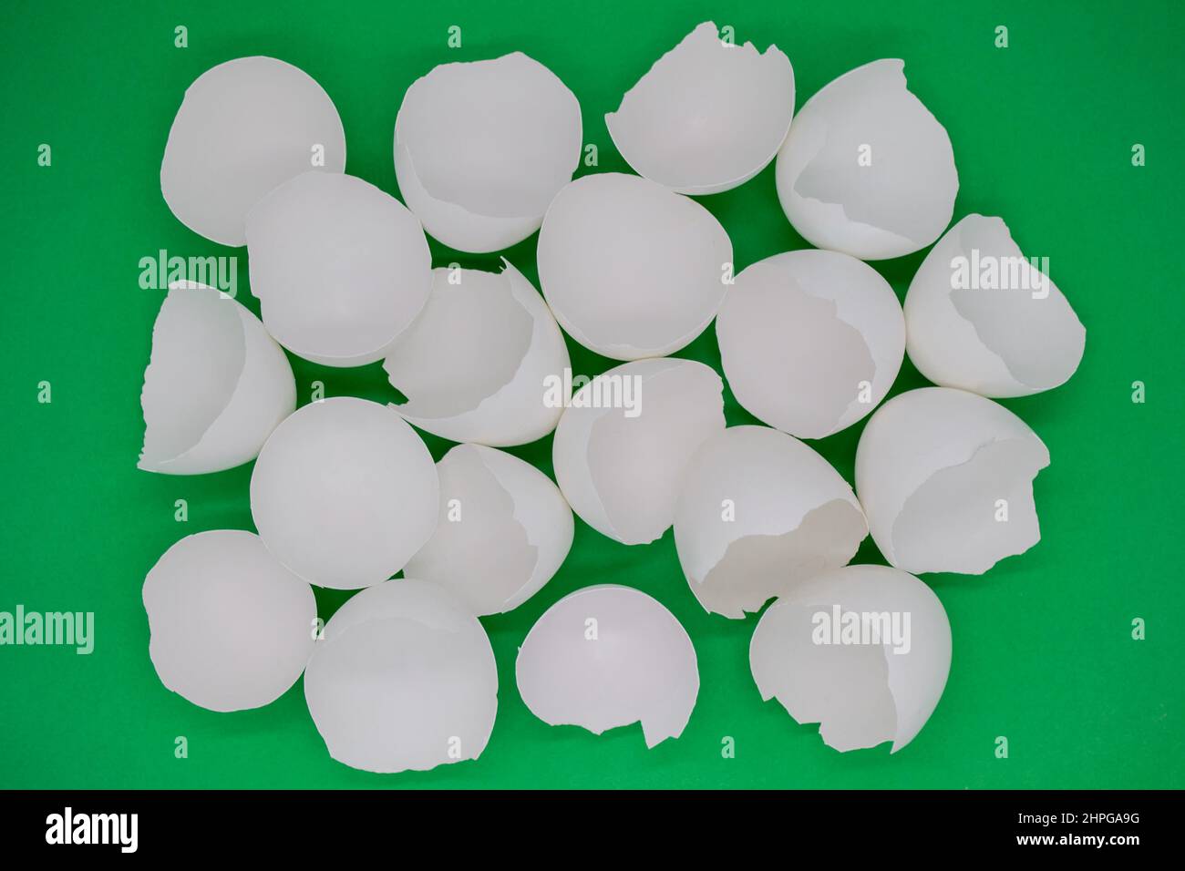 Lots of broken white eggshells on a green background. Copy space. Stock Photo
