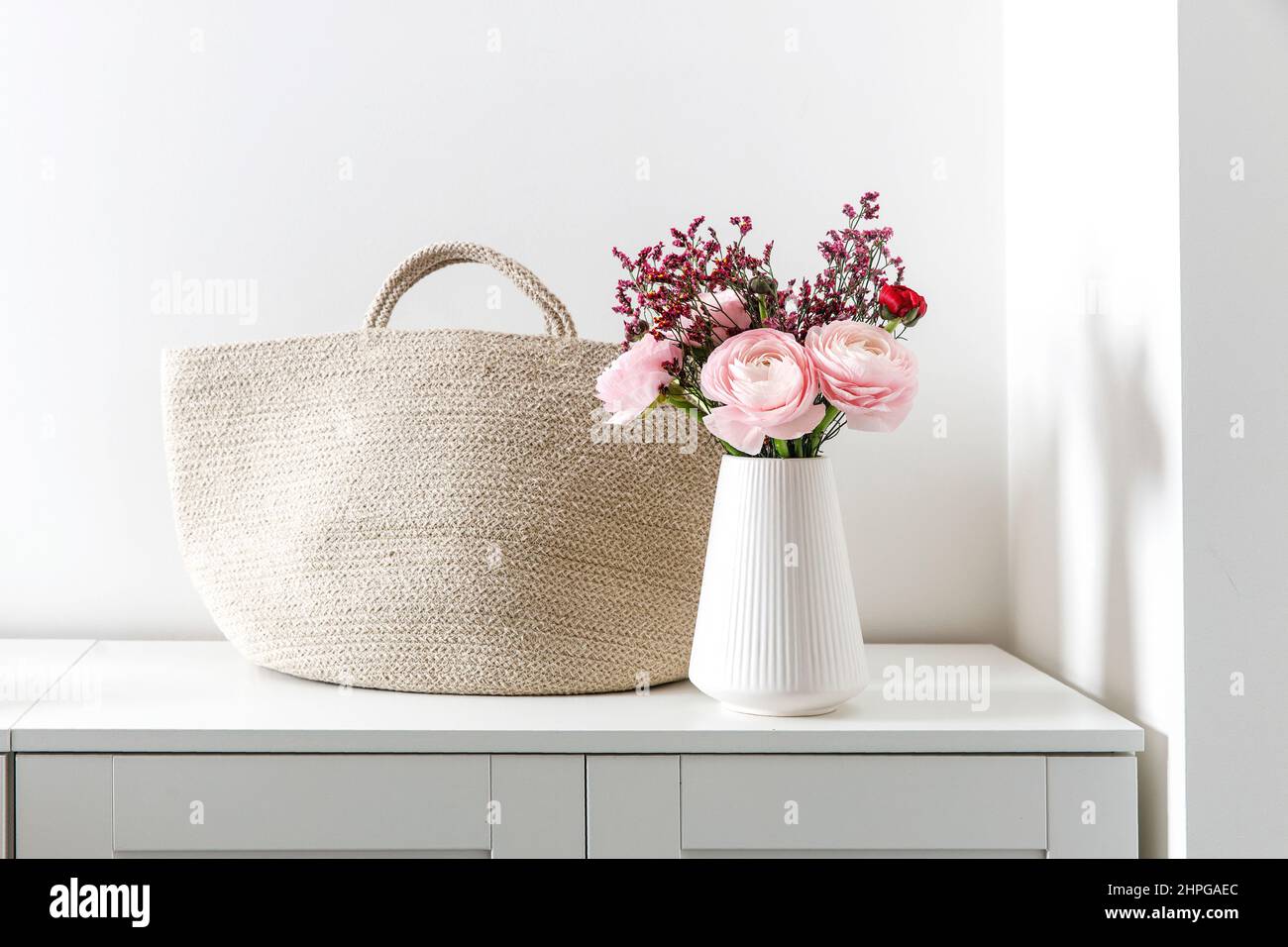 Persian pink buttercup in a beige wicker basket on a white background. Copy space Stock Photo