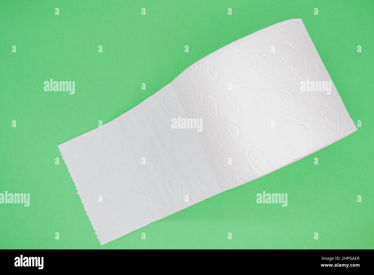 Top view of roll of white toilet paper with perforation on a green background. Copy space. Stock Photo