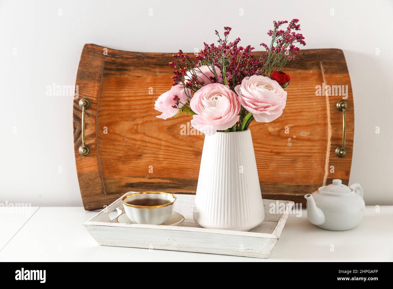 Persian pink buttercup with the wooden brown tray on a white table. Copy space Stock Photo