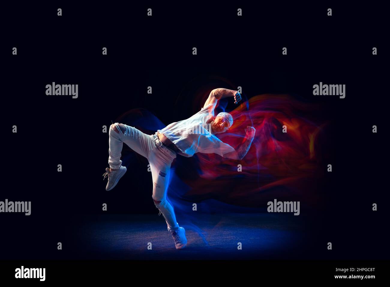 Sportive man in sports white suit dancing hip-hop isolated on dark ...