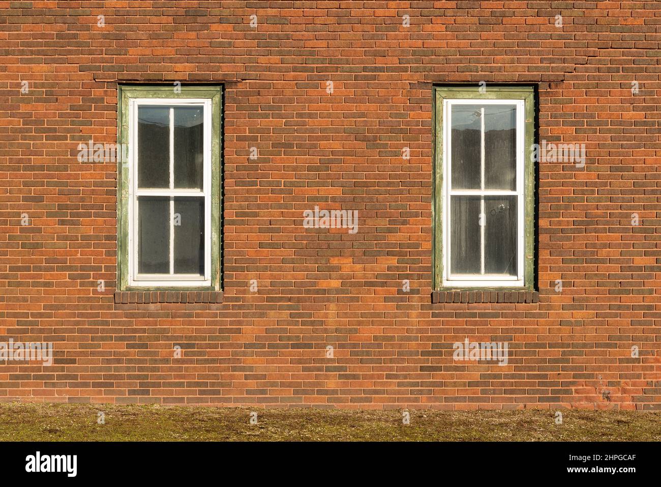 Red brick wall with two windows. Stock Photo