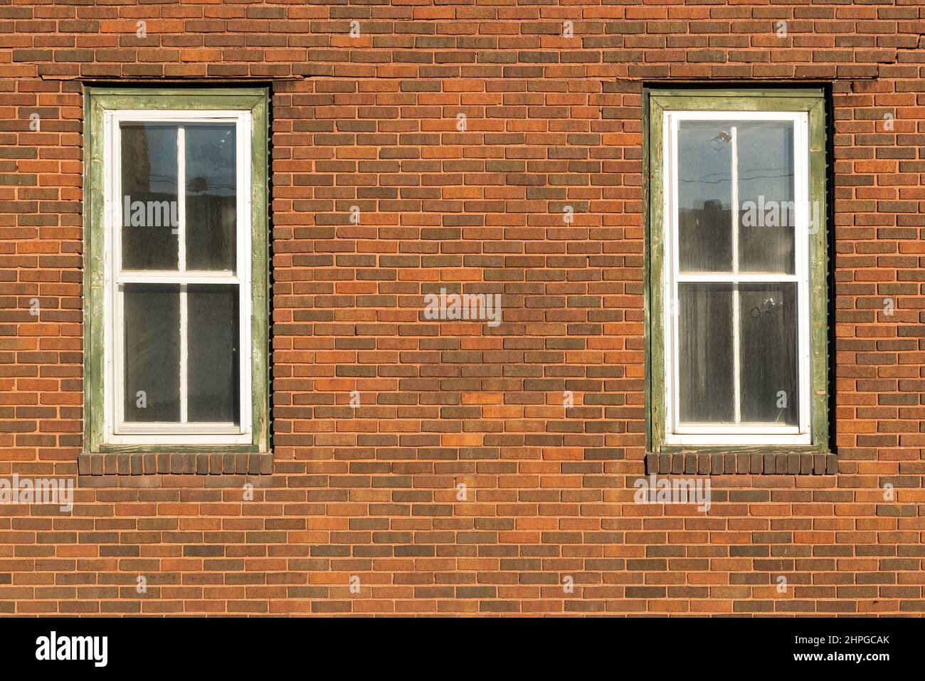 Red brick wall with two windows. Stock Photo