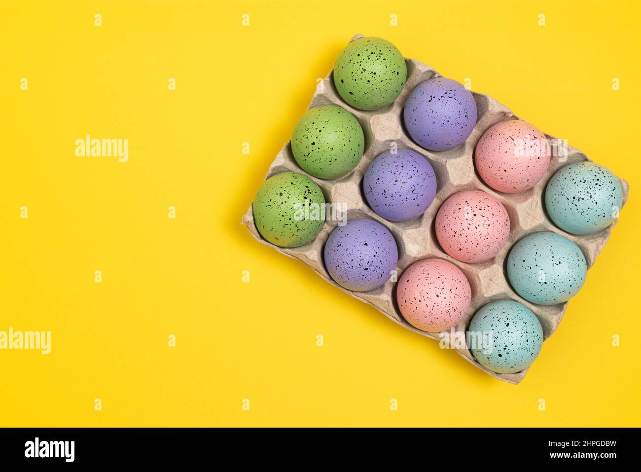 Colorful Easter eggs in egg carton. Flat lay Easter Celebration background with copy space Stock Photo