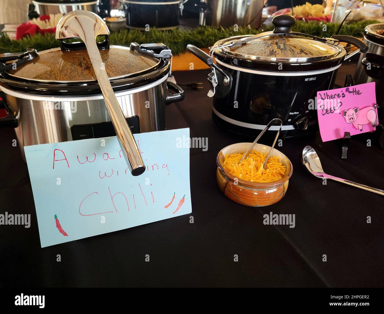 A row of crockpots on a tablecloth in a chili cook-off contest Stock Photo