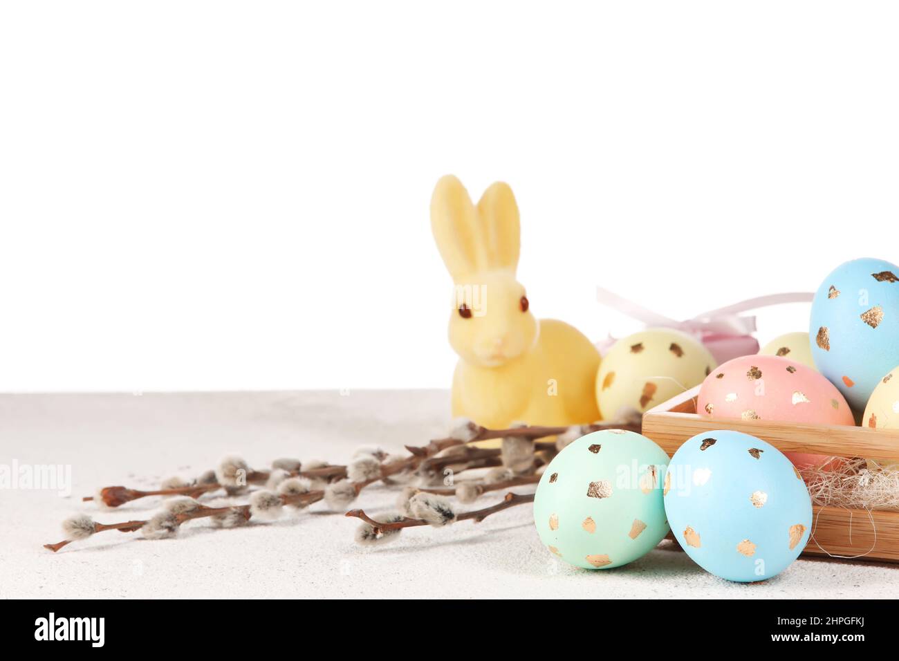 Box with painted Easter eggs, willow branches and bunny on table ...