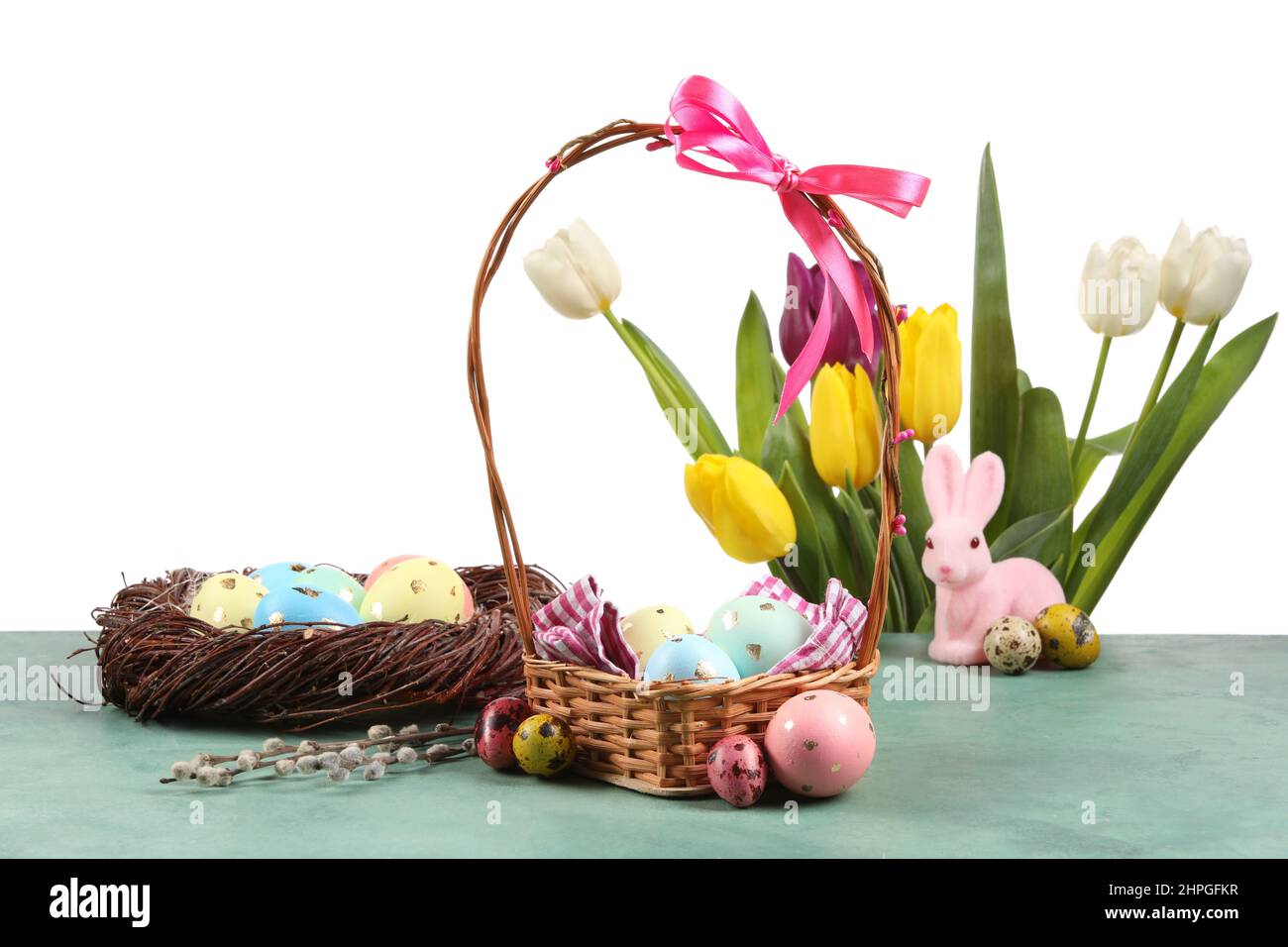 Basket and nest with painted Easter eggs and tulip flowers on table ...