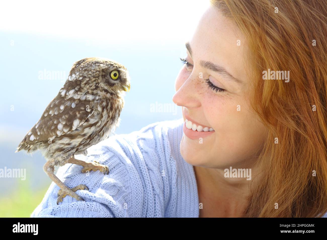 Beautiful woman with an owlet looking each other in nature Stock Photo